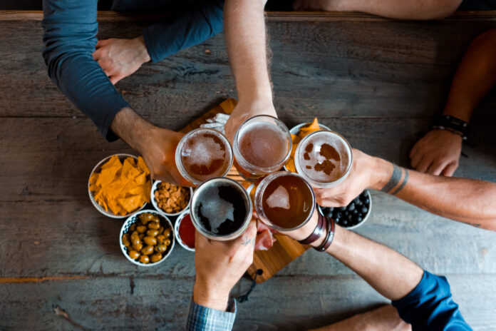 Top view of friends toasting with beer above the table in pub